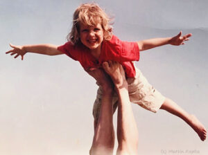 Ein glücklicher Junge streckt Arme und Beine ab und genießt das Segeln im Himmel auf den ausgestreckten Armen.