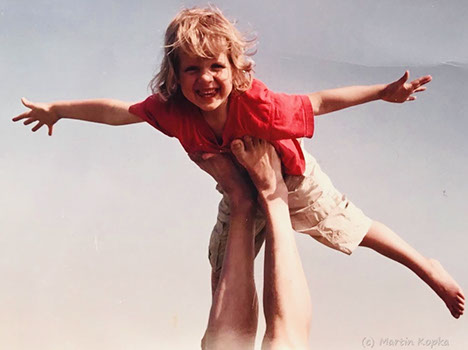 Ein glücklicher Junge streckt Arme und Beine ab und genießt das Segeln im Himmel auf den ausgestreckten Armen.
